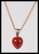 A 9ct gold necklace chain having a 9ct gold red stone set heart pendant. Weighs 5 grams. Chain