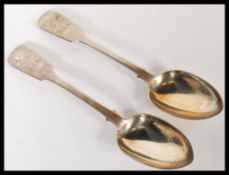 A pair of 19th Century Victorian silver hallmarked fiddle pattern table serving spoons, each spoon