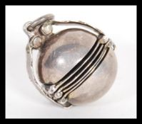A sterling silver early 20th Century metamorphic locket pendant of orb form opening to reveal