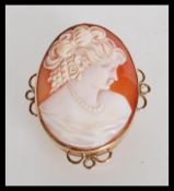 A 9ct gold hallmarked ladies shell cameo brooch. The central cameo depicting maiden inset to an oval