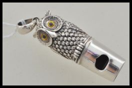A stamped sterling silver whistle in the form of an owl having yellow and black glass eyes, bale