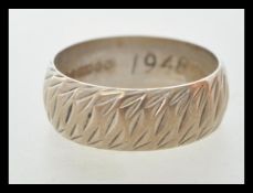 A hallmarked 9ct white gold ring with engraved patterning to the exterior. Hallmarked Birmingham
