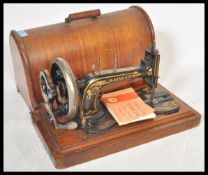 A 19th Century Victorian Singer sewing machine housed within domed wooden case with brass twist lock