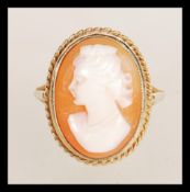 A 9ct gold ladies cameo ring depicting a maiden in shell carving with gadrooned oval mount. Size