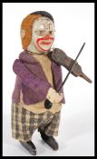 A 1940's Schuco wind-up tinplate clockwork Clown violin player, wearing a felt purple coat and plaid