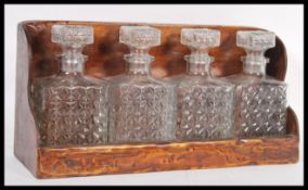 An early 20th Century four decanter set of tantalus manner square form having cut glass design