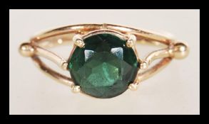 A 9ct gold stamped ring having a large central prong set faceted green stone with gold ball finial