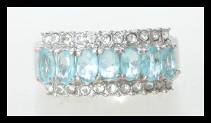 A white metal stamped 10k dress ring having central line of blue faceted stones flanked by two