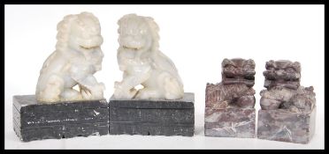 Two pairs of 20th Century carved soapstone temple dogs, the larger pair raised on carved ebonised