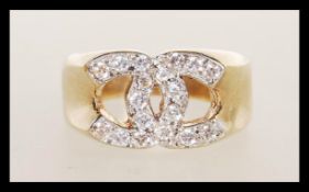 A 9ct gold 9k stamped designer ring in the manner of Channel having white stone set cross C design