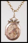 A late 19th / early 20th Century Victorian 9ct gold locket of oval form having scrolled engraving to
