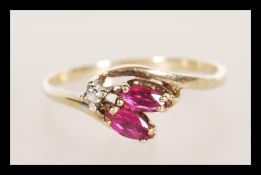 A hallmarked 9ct gold diamond and garnet stone ring having a prong set diamond with faceted red