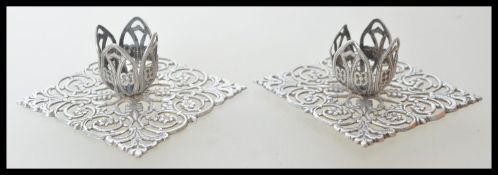 A pair of Chinese silver candlesticks of stub form raised on square bases having intricate pierced