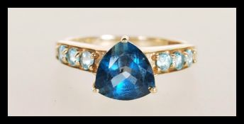 A hallmarked 9ct gold ring set with a triangular cut blue stone with light blue accent stones to the