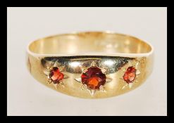 A hallmarked 9ct gold three stone garnet ring having three flush set faceted red stones. Weighs 2.