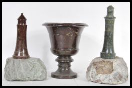 A group of carved Cornish serpentine ware to include two lighthouses on rock bases and a vase raised