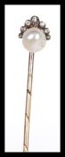 An early 20th Century unmarked yellow metal hat pin having a pearl finial to the top set with