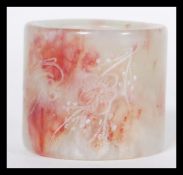 A Chinese large mottled dark green and red jade archer's thumb ring of cylindrical form. Measures