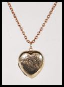 A 20th Century stamped 9ct gold heart locket having scrolled engraving to the front on an unmarked