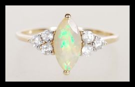 A hallmarked 9ct gold ring set with a marquise cut opalescent stone flanked with six white accent