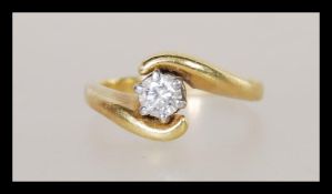 An unmarked but tests as 18ct gold and diamond having a brilliant cut diamond in a crossover