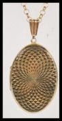 A 9ct gold oval shaped hallmarked locket with engine turned decoration being set to a 9ct gold