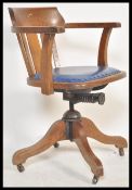 A vintage early 20th century Industrial oak office chair raised on a quadruped swivel base having