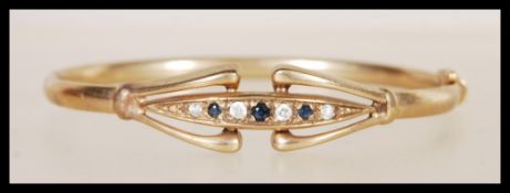 A vintage 9ct gold bangle bracelet of circular form having a flush row of black and white stones