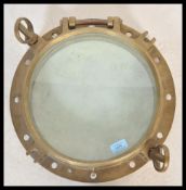 A vintage 20th Century large brass framed nautical ships window porthole having inset glass panel
