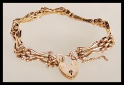 A 20th Century stamped 9ct gold heart lock bracelet with a decorative link design. Total weight 13.