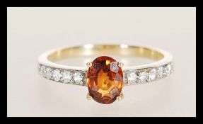 A hallmarked 9ct gold ring prong set with an oval cut brown having white accent stones to the