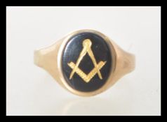 A hallmarked 9ct gold ring set with a oval onyx panel with a gilt masons symbol. Hallmarked London