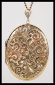 A hallmarked 9ct gold large locket pendant of oval form set to a 9ct gold curb link chain. Chased