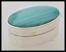 A silver pill / trinket box of oval form having a green malachite set lid. Weight 26.0g.