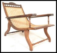 A 19th century Victorian Colonial teak and cane plantation chair, with swing out leg rests raised on
