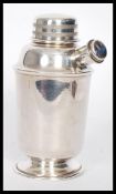 A silver plated Art Deco style cocktail shaker raised on a round base with a corked pouring spout to