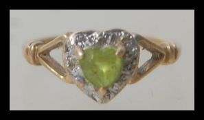 A hallmarked 9ct gold ring having a central heart shaped peridot stone with a halo of white