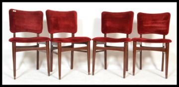 A set of four vintage retro 20th Century dining chairs raised on tapering legs with red velour seats