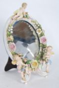 A 19th Century style porcelain easel back mirror, oval form, florally encrusted with lappet and