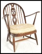 A mid 20th Century Ercol wheelback dining chair with railed arch back rest, raised on turned