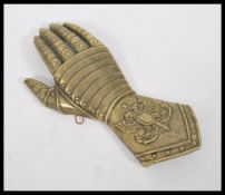 An antique style bronze / brass wall plaque in the form of a gauntlet and bracer outstretched hand