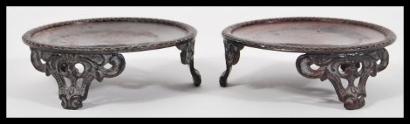 A pair of Chinese / Japanese bronze vase stands of circular form raised on scrolled bases.