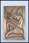 A 20th Century wall hanging bronzed plaque depicting a seated partially naked lady playing a lyre in