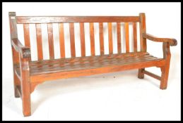 A good sized large solid teak wood garden bench of slatted form with shaped elbow rests either