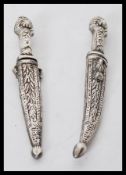 A pair of 20th Century silver white metal miniature daggers in sheafs having floral and leaf