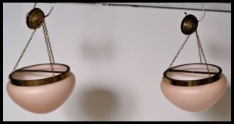 A pair of vintage retro 20th Century ceiling lights having a brass ceiling bracket with a dusty pink