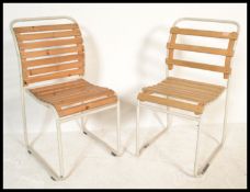 A pair of vintage retro 20th Century stacking chairs having slatted wood seats and backs raised on
