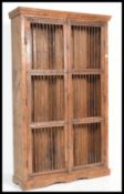 A late 20th Century antique style teak large cupboard / bookcase having a metal grilled front.