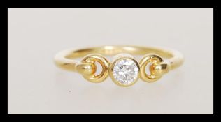 A hallmarked 18ct gold ring set bezel set with a brilliant cut diamond with decorative looped
