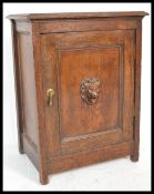An early 20th Century unusual oak cabinet / pot cupboard having a single carved lion mask to the